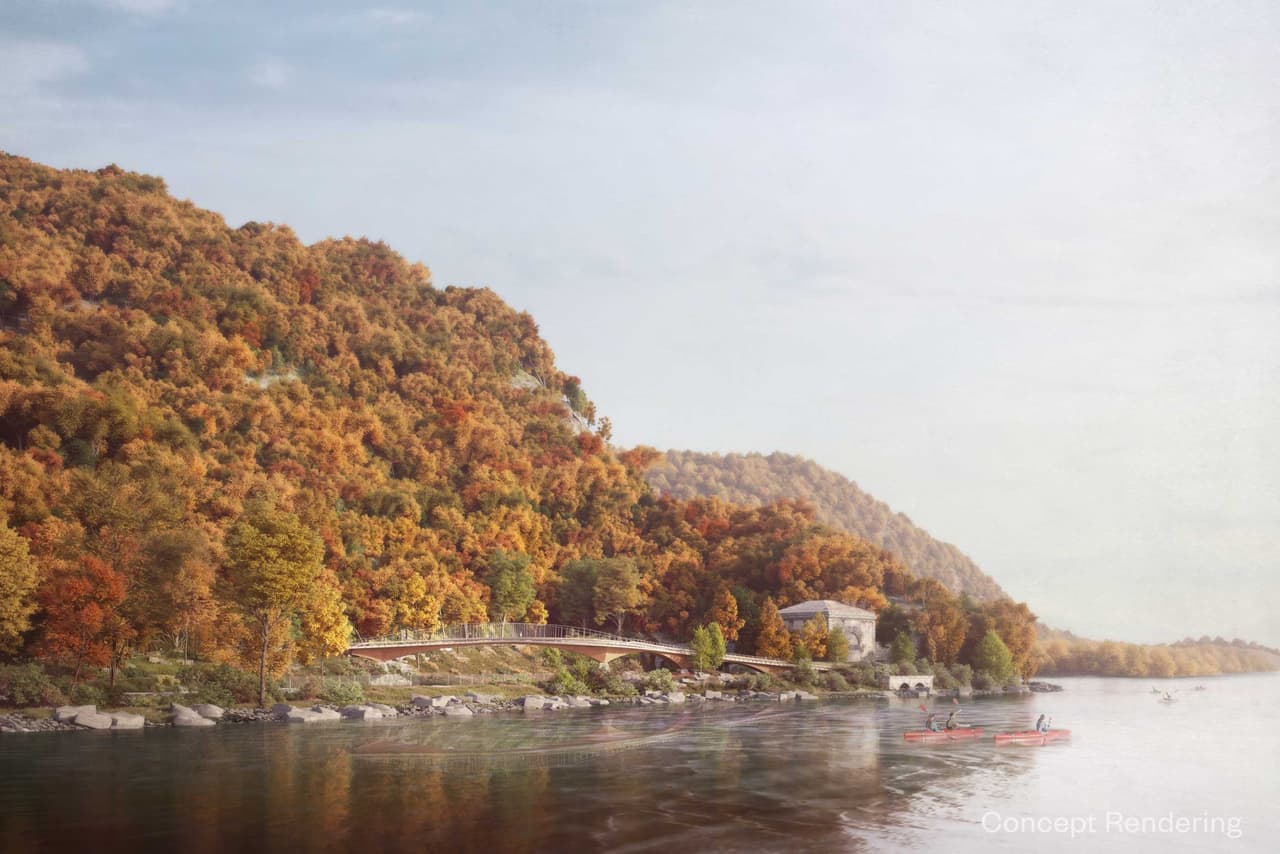 Artist's rendering of the proposed Breakneck Connector seen from the river in autumn: a slender bridge structure low against the foot of a mountainside in full orange and russet colour, with two kayakers on the water in the foreground.