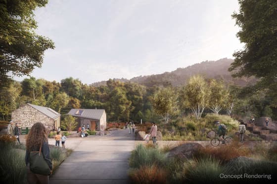 Artist's rendering of the proposed restroom building at Breakneck: a low stone structure with a shallow roof at the edge of a gravel plaza, people and cyclists moving across the open space, wooded hills behind.
